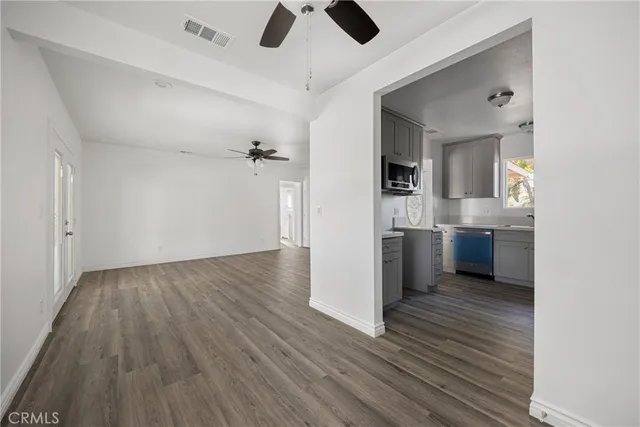 a view of kitchen and empty room with wooden floor