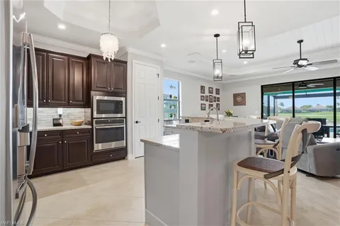 a large kitchen with kitchen island granite countertop a stove a sink a refrigerator dining table chairs and cabinets