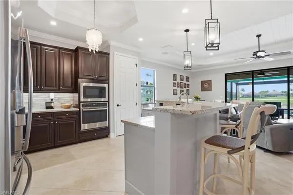 a large kitchen with kitchen island granite countertop a stove a sink a refrigerator dining table chairs and cabinets