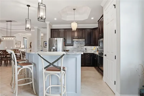 a kitchen with stainless steel appliances kitchen island granite countertop a refrigerator a oven a sink with a dining table and chairs
