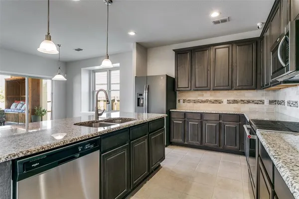 a kitchen with stainless steel appliances granite countertop a sink a stove and a refrigerator