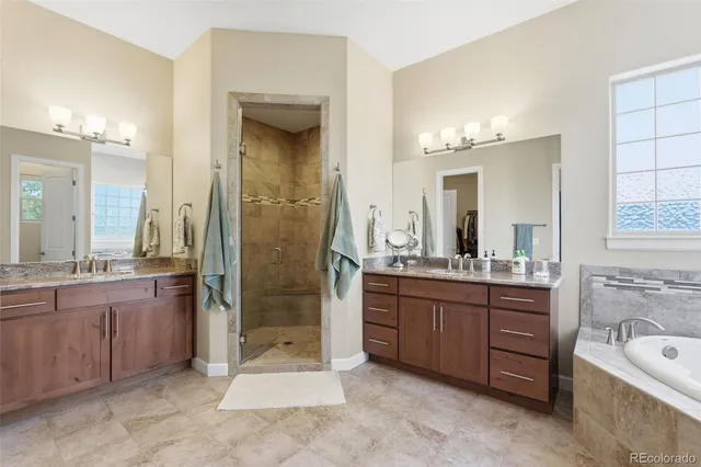a bathroom with a granite countertop tub sink shower and mirror