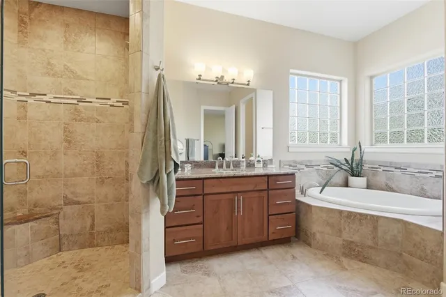 a bathroom with a granite countertop tub sink and mirror