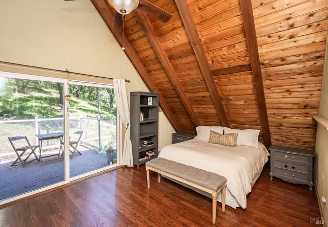 a bedroom with a bed a table and wooden floor