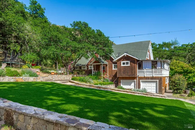 a view of a house with a big yard plants and large trees