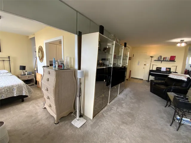 a living room with furniture a flat screen tv and a refrigerator