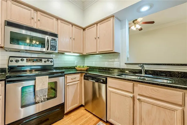 a kitchen with granite countertop white cabinets stainless steel appliances and a sink