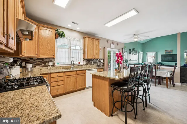 a kitchen with stainless steel appliances granite countertop a stove top oven a sink dishwasher and cabinets with wooden floor