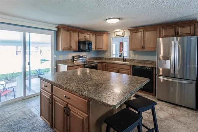 a kitchen with stainless steel appliances granite countertop a stove top oven a refrigerator a sink and a granite counter tops