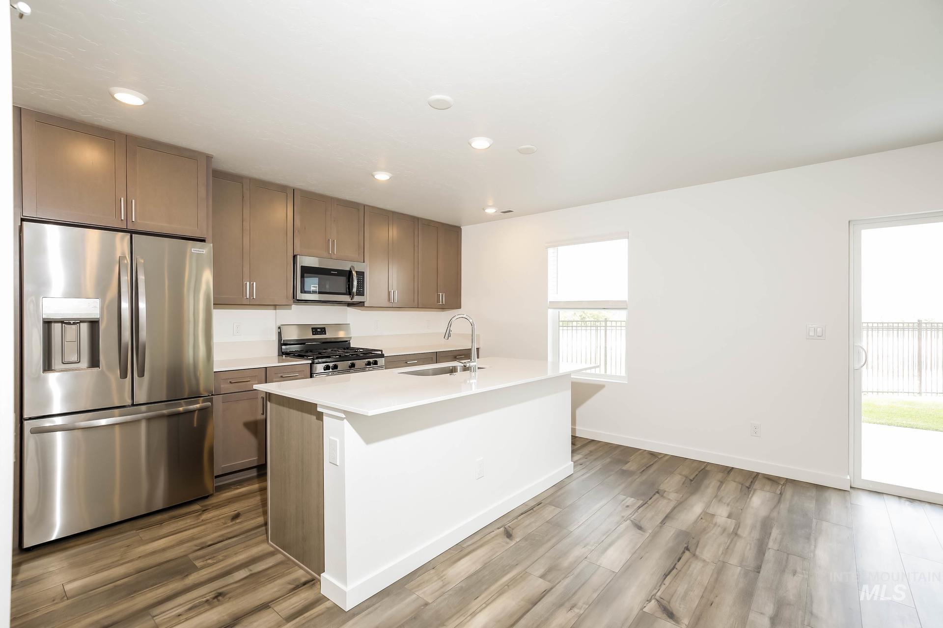 Kitchen featuring stainless steel appliances, wood-finish flooring, white countertops, a kitchen island, and recessed lighting