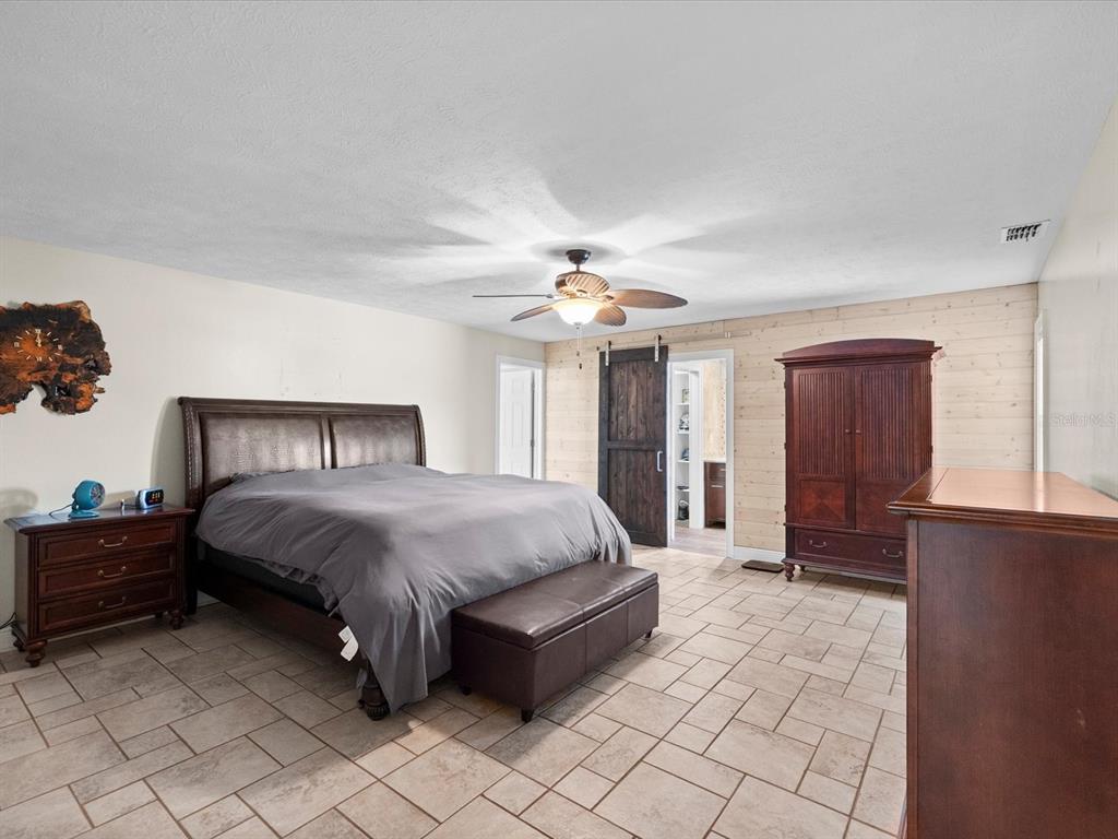 5904 Springrun Court Holiday, FL 34690 - Photo 23 of 53 a spacious bedroom with a bed and a chandelier