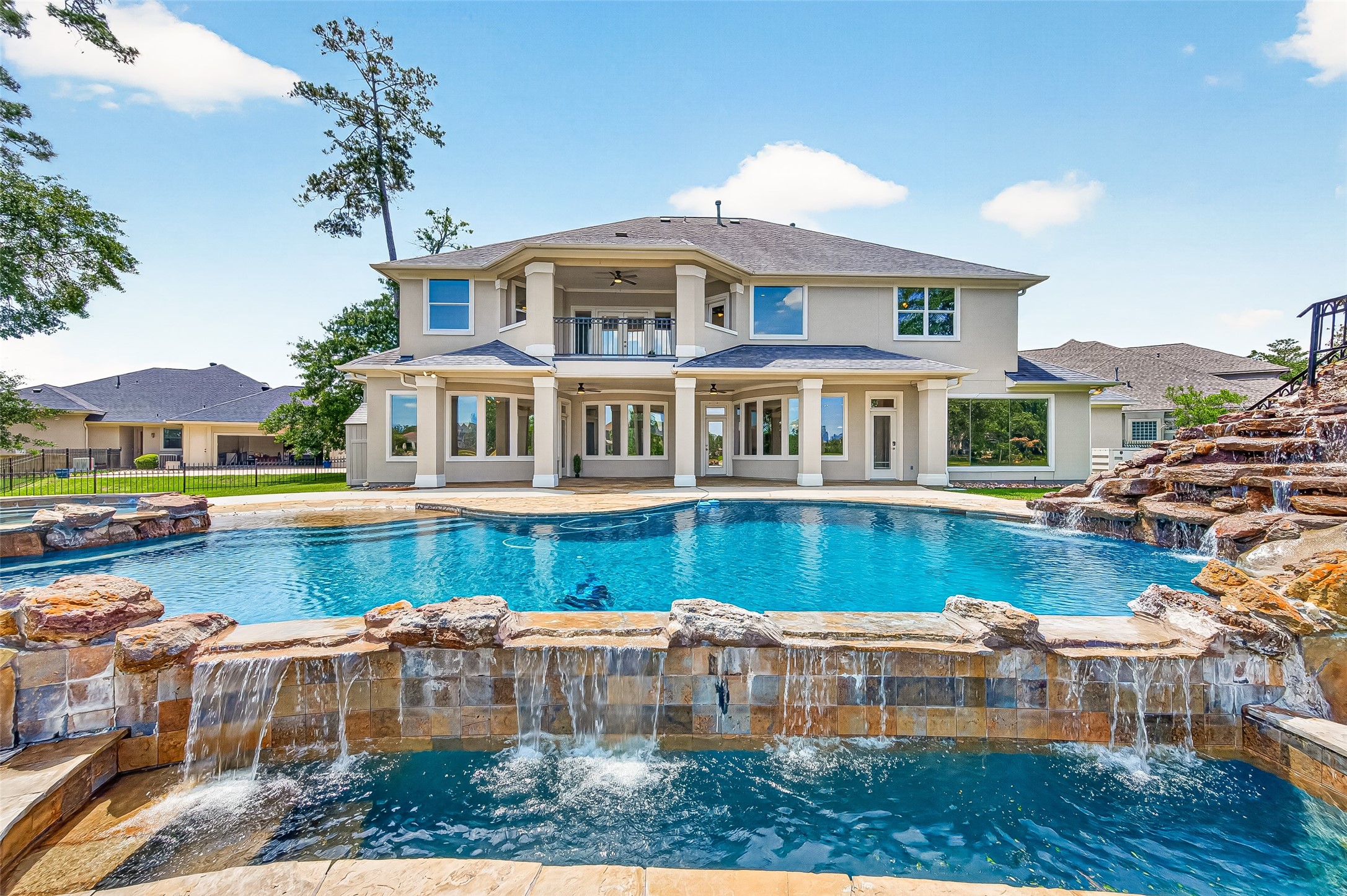 25626 Windy Isle Court Spring, TX 77389 - Photo 21 of 45 This stunning two-story home features a luxurious backyard with a large pool, waterfall, and spacious patio, plus a covered balcony, perfect for outdoor living.