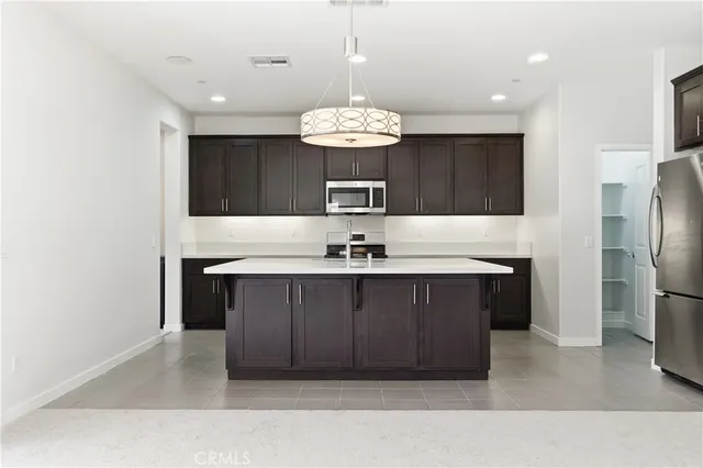 a kitchen with stainless steel appliances a chandelier and refrigerator