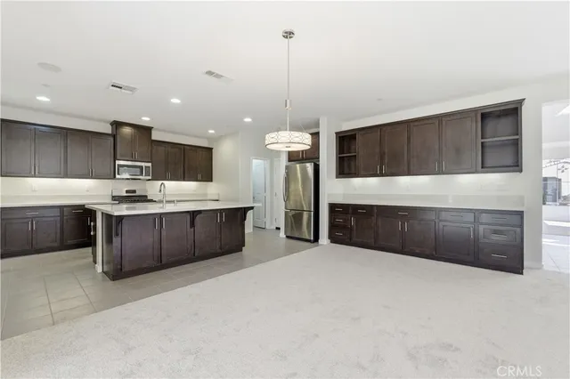 a large kitchen with a large counter top a sink stainless steel appliances and cabinets