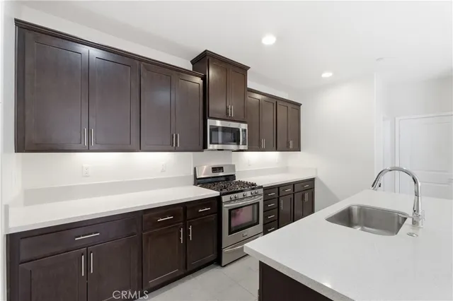 a kitchen with a sink dishwasher a stove and a refrigerator with wooden cabinet