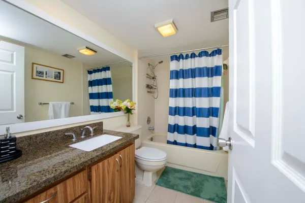 a bathroom with a granite countertop sink a toilet a mirror a shower and a bathtub