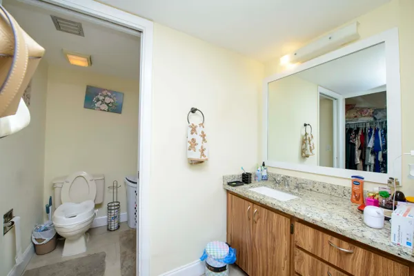 a bathroom with a granite countertop sink mirror vanity and toilet