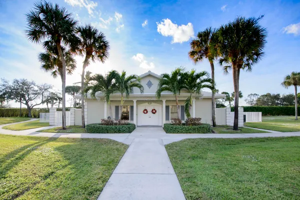 front view of a house with a yard and palm trees
