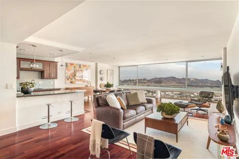 a living room with furniture a rug and kitchen view