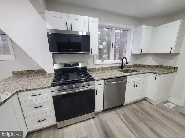 a kitchen with granite countertop a stove a sink and a microwave