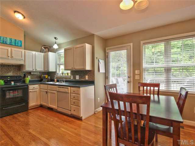 4309 Pillory Place Raleigh, NC 27616 - Photo 6 of 23 a kitchen with stainless steel appliances granite countertop a stove top oven a sink dishwasher a dining table and chairs with wooden floor
