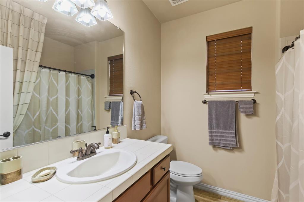 9116 Perimeter Street Denton, TX 76207 - Photo 4 of 26 a bathroom with a sink a toilet a mirror and shower curtain