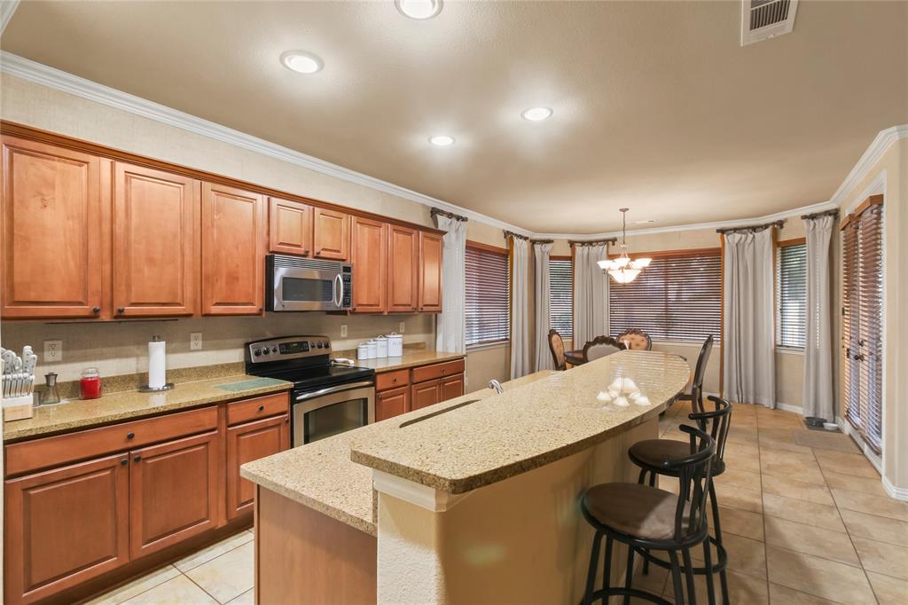 9116 Perimeter Street Denton, TX 76207 - Photo 8 of 26 a kitchen with stainless steel appliances granite countertop a stove top oven a sink dishwasher and a refrigerator with wooden cabinets