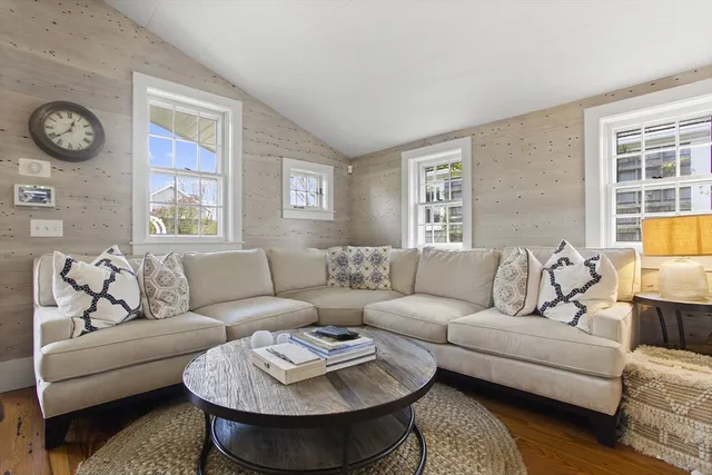 a living room with furniture a clock on wall and a window