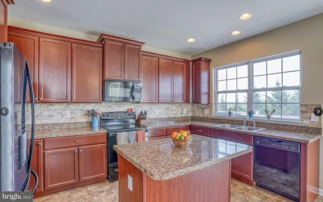 a kitchen with stainless steel appliances granite countertop wooden cabinets a sink and dishwasher next to a window