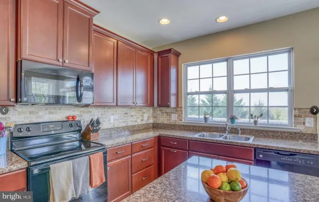 a kitchen with stainless steel appliances granite countertop a sink and a window