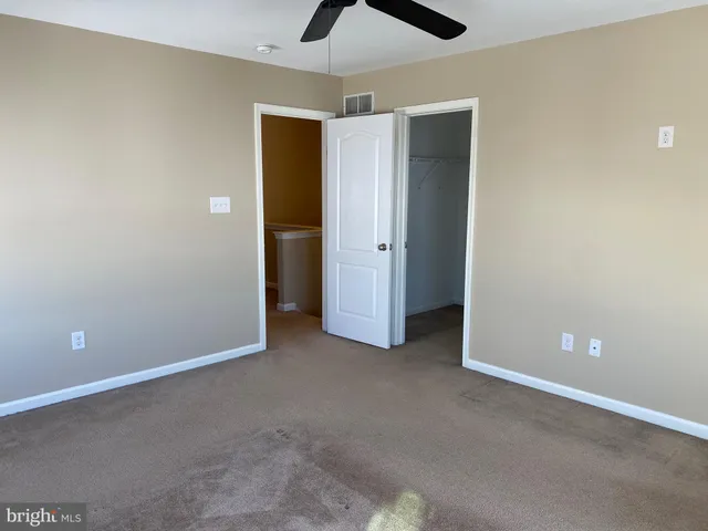 an empty room with closet and a chandelier fan
