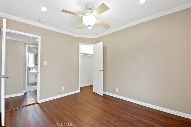 an empty room with wooden floor and a ceiling fan