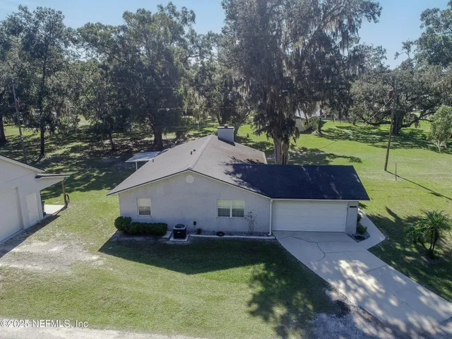 an aerial view of residential house with outdoor space and trees all around