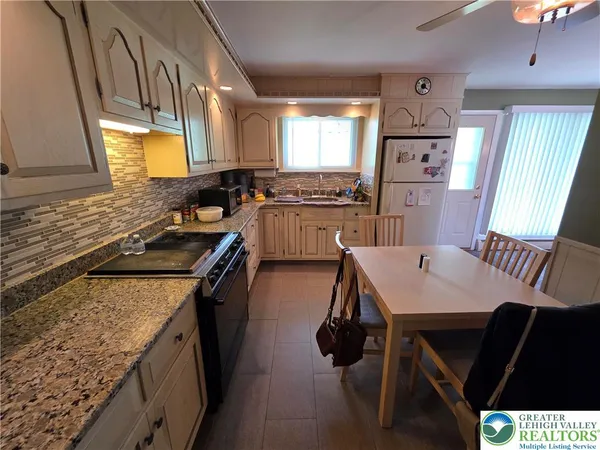 a kitchen with a sink a stove a refrigerator a dining table and chairs