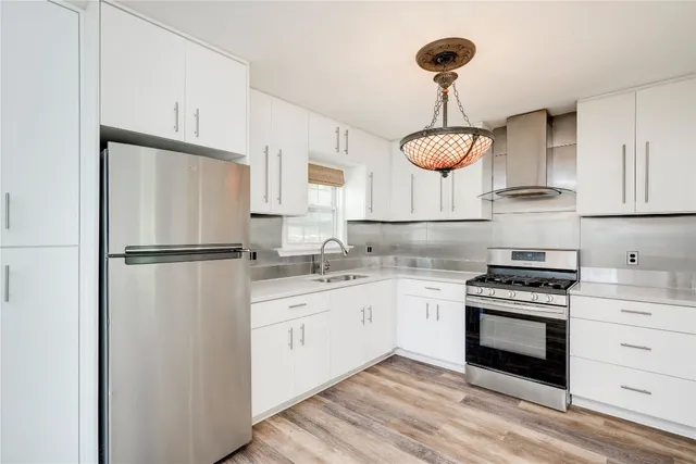 a kitchen with stainless steel appliances granite countertop a sink a stove and a refrigerator