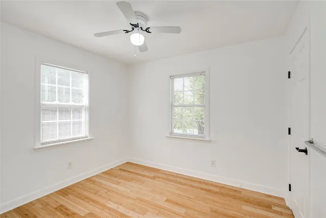 a view of an empty room with a window and wooden floor
