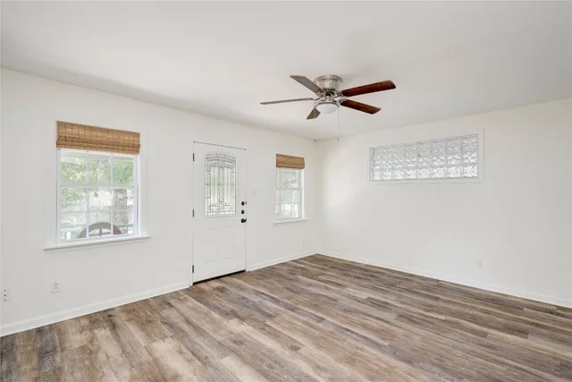 a view of empty room with wooden floor and fan