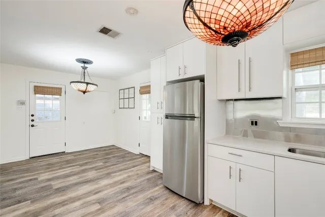 a kitchen with stainless steel appliances granite countertop a refrigerator sink and white cabinets