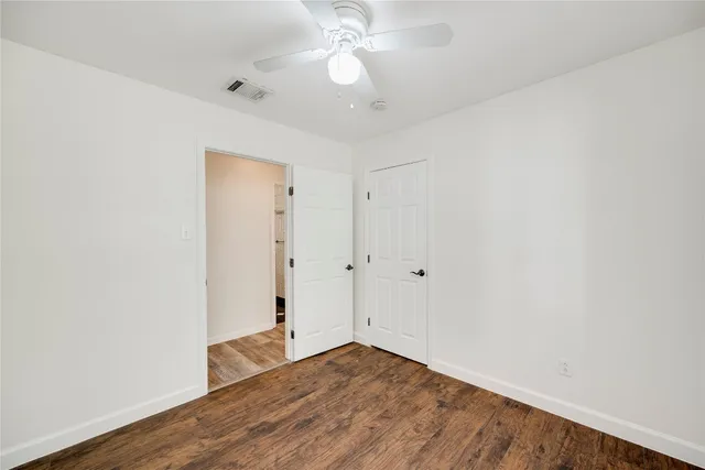 an empty room with wooden floor and fan