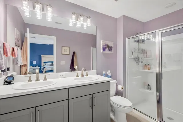 a bathroom with a shower sink vanity mirror and toilet