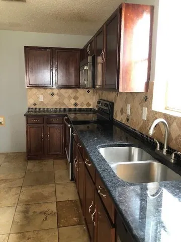 a kitchen with granite countertop a stove top oven microwave and cabinets