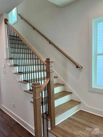 a view of an empty room with wooden floor and windows