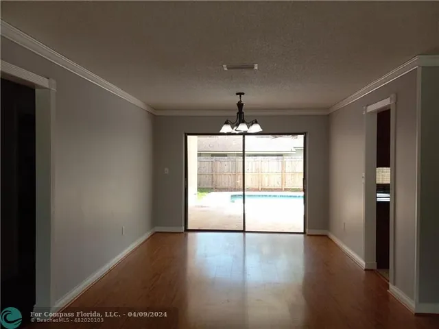 an empty room with wooden floor and chandelier