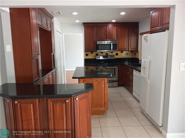 a kitchen with stainless steel appliances granite countertop a refrigerator and a stove top oven
