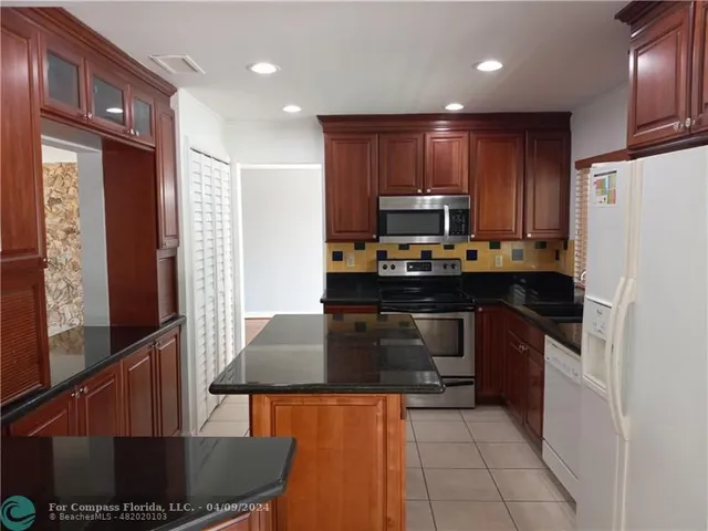 a kitchen with kitchen island granite countertop wooden cabinets a refrigerator and a stove