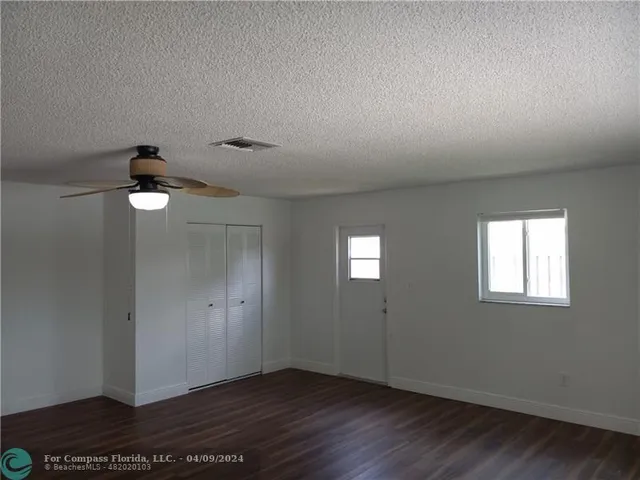 an empty room with wooden floor cabinet and windows