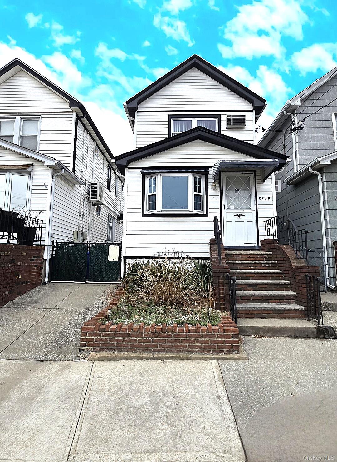 View of front of house with driveway, fence, and a gate
