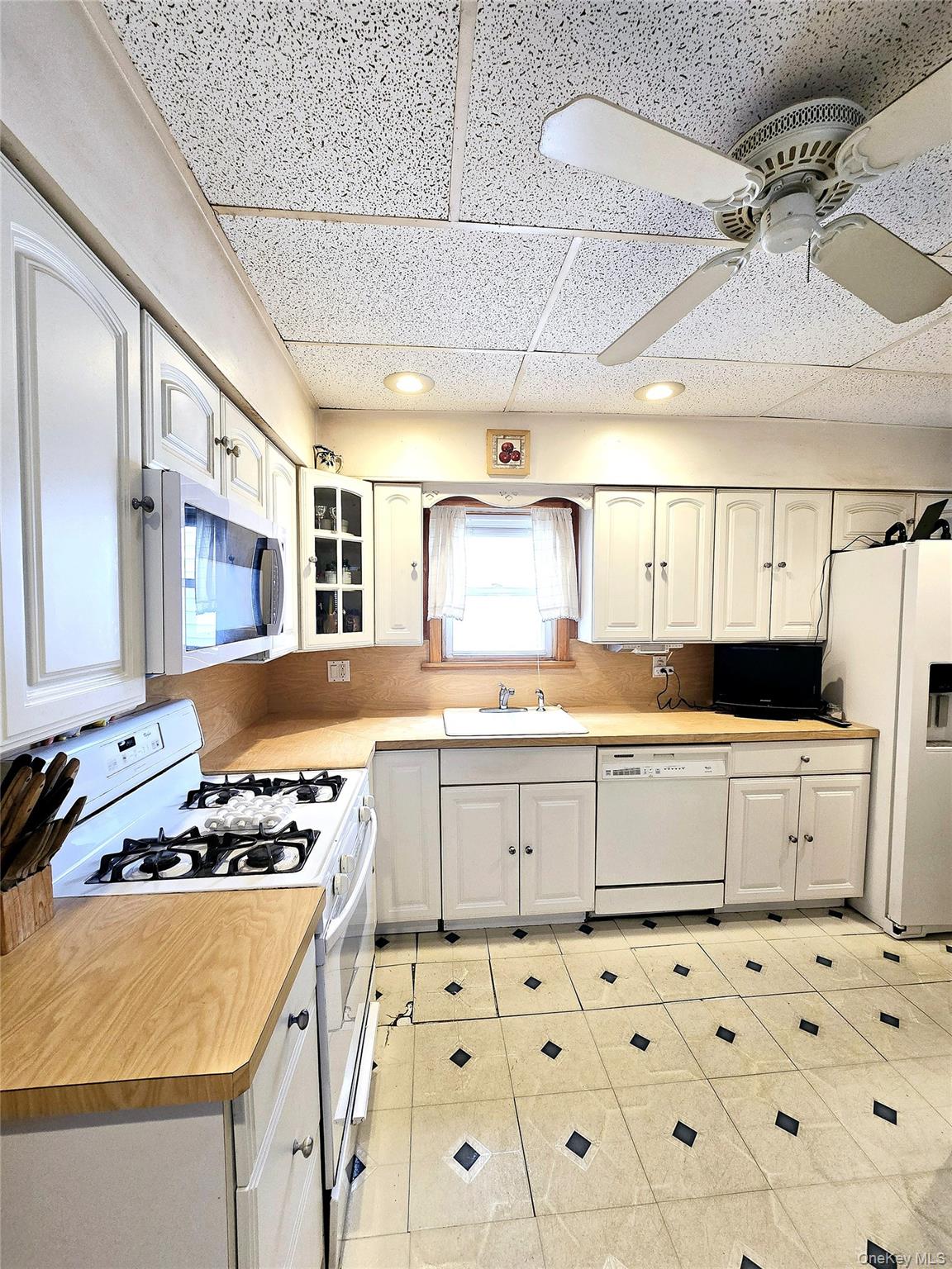 85-09 Sutter Avenue Queens, NY 11417 - Photo 2 of 12 Kitchen featuring a sink, white appliances, light countertops, glass insert cabinets, and ceiling fan