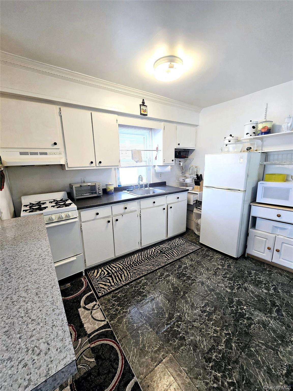 85-09 Sutter Avenue Queens, NY 11417 - Photo 3 of 12 Kitchen with under cabinet range hood, a sink, white cabinetry, white appliances, and crown molding