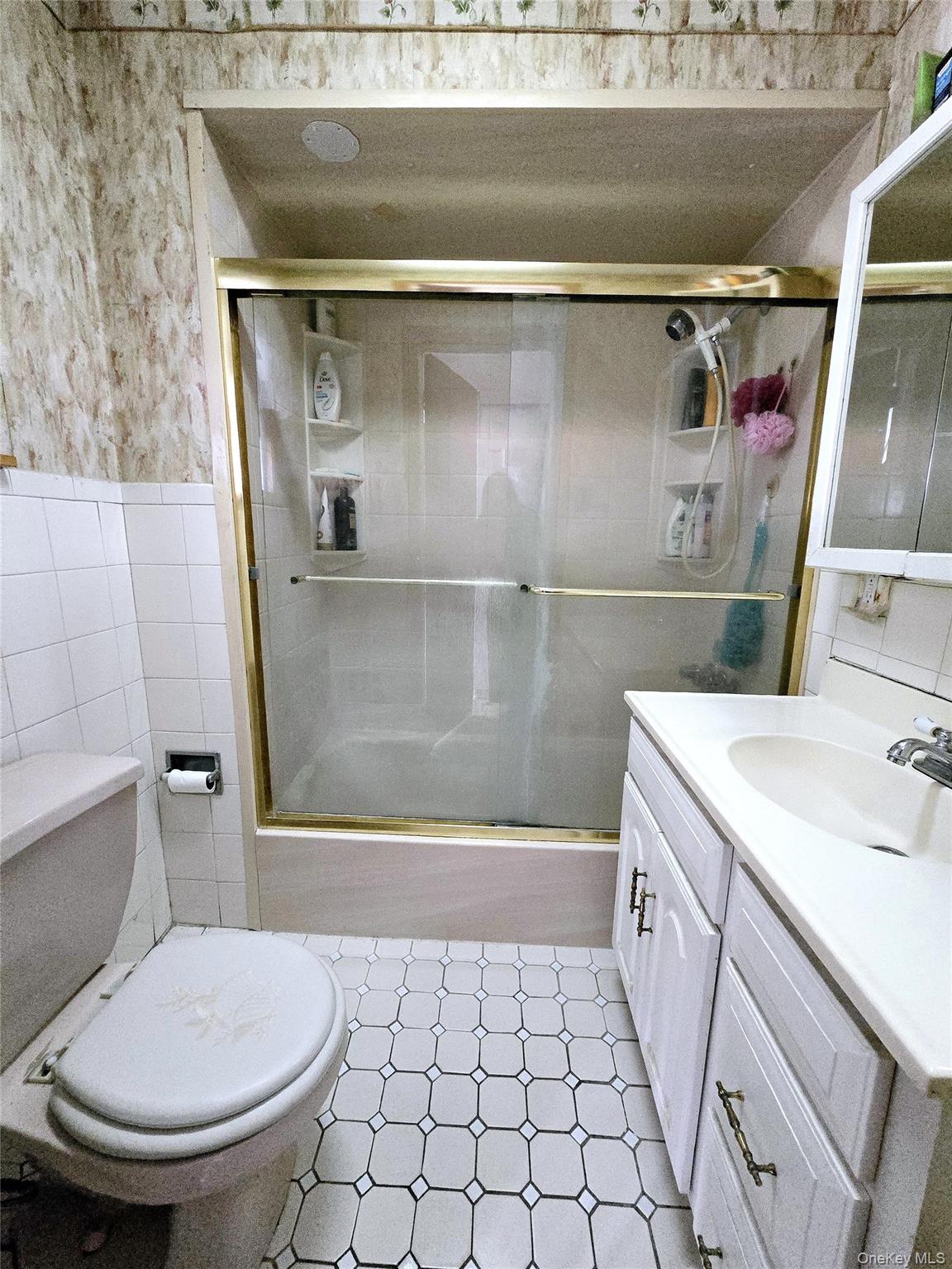 85-09 Sutter Avenue Queens, NY 11417 - Photo 7 of 12 Bathroom with wallpapered walls, tile walls, a wainscoted wall, toilet, and vanity